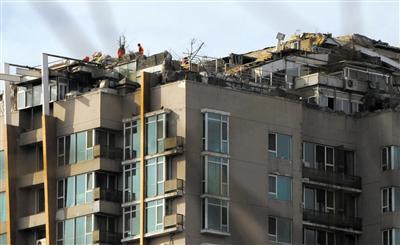 　　昨日，身穿橘黃色馬甲的工作人員在人濟(jì)山莊樓頂拆除違章建筑。新京報(bào)記者 吳江 攝