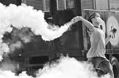 12月2日，泰國曼谷，一名反政府示威者在總理府附近向負責執(zhí)勤的警察投擲催淚彈。英拉請求示威者不要再試圖占領政府工作部門，不要逼迫政府工作人員選邊站。