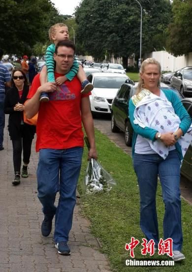 圖為一個(gè)白人家庭，由父母帶著孩子到曼德拉家門外悼念。中新社發(fā) 宋方燦 攝
