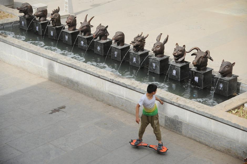 圖為一名市民從獸首旁經(jīng)過。