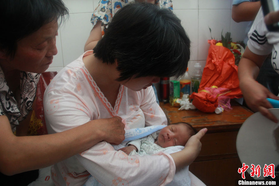 圖為久別重逢，獲救嬰兒母親悉心撫摸愛(ài)子。張一辰 攝