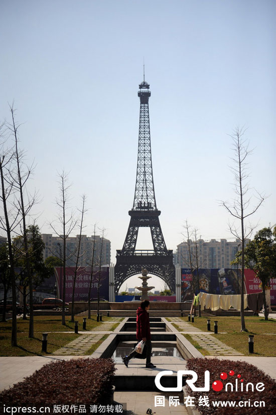 　2014年3月21日，杭州天都城，農(nóng)民在山寨埃菲爾鐵塔下耕作。圖片來源：東方IC