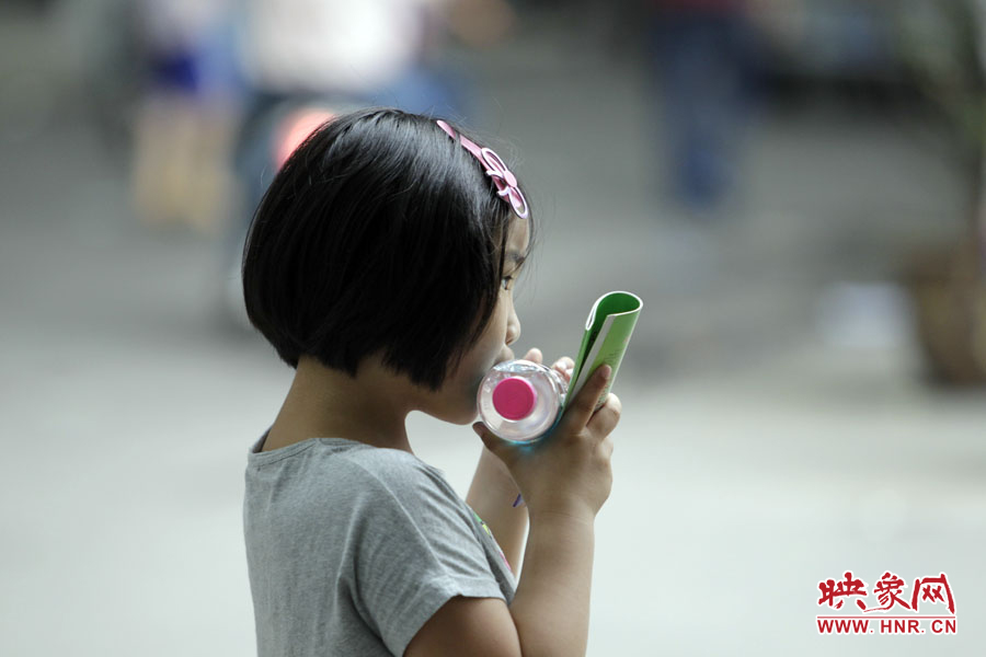 6月7日，鄭州回中考點(diǎn)，一名孩子拿著一瓶礦泉水，等待哥哥走出考場