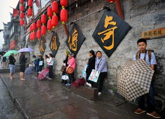 　4月29日上午11時(shí)20分，一些游客和古城當(dāng)?shù)氐木用穸阍谝粋€(gè)酒吧的屋檐下避雨。這些當(dāng)?shù)鼐用褚詾橛慰团恼罩\生，一場(chǎng)降雨讓他們的生意更加清淡。