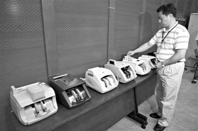 昨日，央行工作人員用各種驗鈔機對C1F9假幣進行測試，機器均能及時作出異常報警反應(yīng)。新京報記者 浦