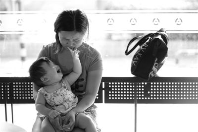 昨日，肯德基京廣中心店門口，姜女士提起跟養(yǎng)父母的關系時落淚，懷中9個月的女兒笑著跟她玩。新京報記者 薛珺 攝