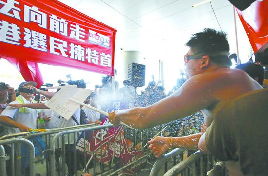 17日，在香港立法會(huì)外，一名反對(duì)政改的男子向支持派人群投擲標(biāo)牌。