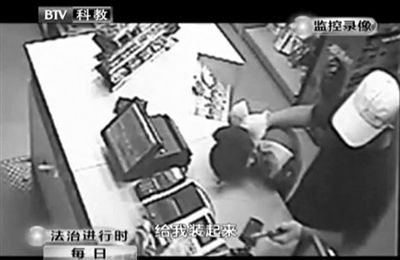 戴帽男子一手掐住加油站營業(yè)員，一手持發(fā)令槍指向另一營業(yè)員，要求“把錢給我裝起來”。