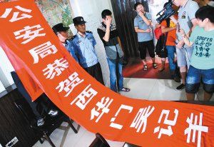 面對警方收繳的條幅，老板楊某也不好意思地用手遮擋臉