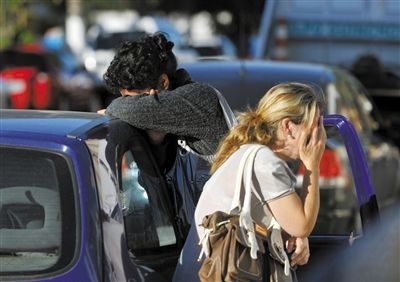 27日，遇難者親友在火災(zāi)現(xiàn)場(chǎng)旁哭泣。