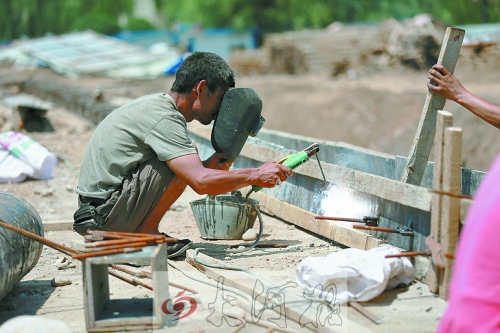 　正午陽光下，工地上的焊接工人還在認(rèn)真工作。