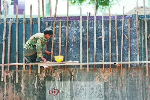 　　烈日下，狹窄的架子上，工人正用錘子固定樁基。