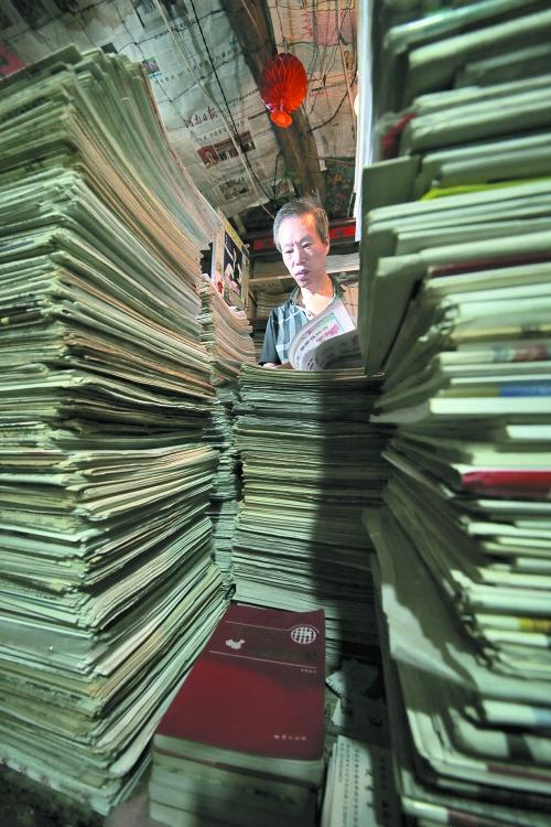 王曉民坐在寫字桌前，被報(bào)紙淹沒。