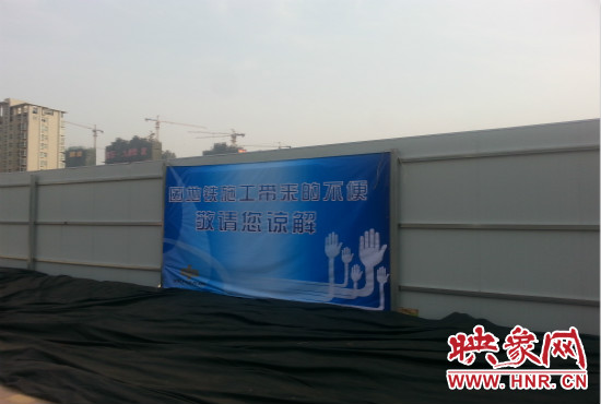 道路南側圍起了白色的圍擋，墻上標示著“因地鐵施工帶來的不便敬請您諒解”的提示牌。