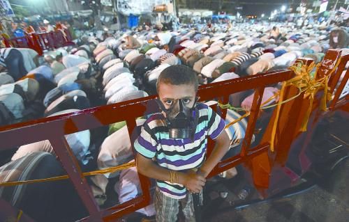 當(dāng)?shù)貢r間28日晚，在埃及開羅納賽爾城，一名小男孩頭戴防毒面具參加穆兄會的集會示威。