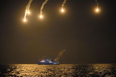 22日，搜救人員在照明彈的光亮下連夜搜救。