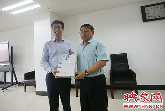 阿里云計(jì)算總裁胡曉明向河南省新聞出版廣電局局長朱夏炎遞交《中原云平臺(tái)交付手冊(cè)》。