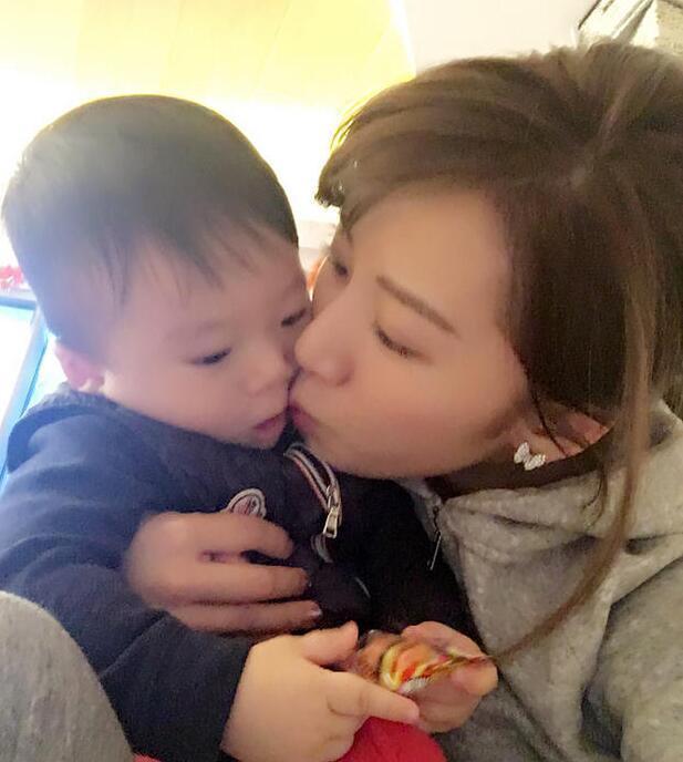 照片中李念狂吻兒子，小寶貝自顧自地玩著。