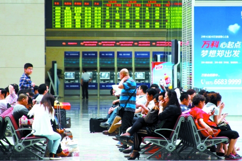 候車大廳溫度很高，一名乘客一手扇風、一手擦汗