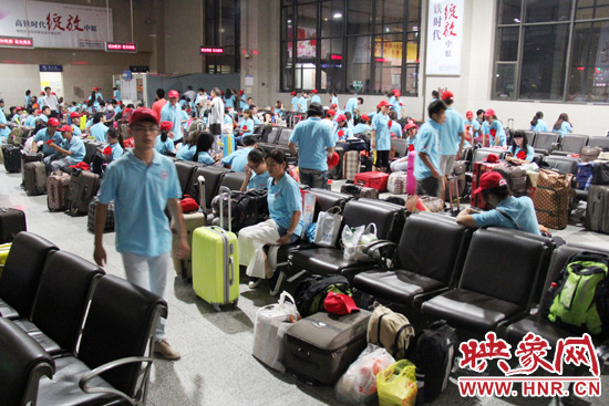 大學(xué)生志愿者在火車站候車室內(nèi)整裝待發(fā)。