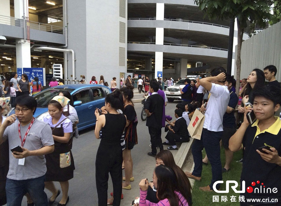 當(dāng)?shù)貢r(shí)間2014年5月5日，泰國清萊，工人們站在一棟大樓外避難。