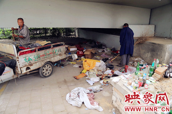 負(fù)責(zé)高架橋下綠化的人員在清理流浪漢留下的垃圾和雜物。