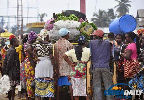 當地時間2014年8月14日，利比里亞蒙羅維亞，市場里的商人們圍著一輛汽車。