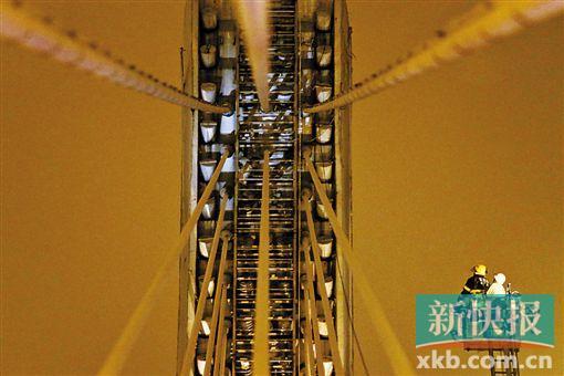 截至今日零時(shí)，男子仍未有下橋舉動(dòng)。圖為公安和消防人員乘消防云梯在高空上和男子交談。